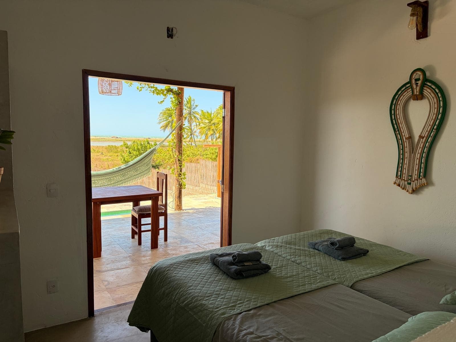 Chambre ouverte de plain-pied sur la terrasse, le hamac et la lagune