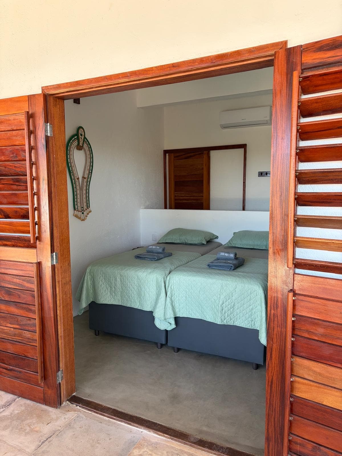 Chambre à deux lits, vue depuis la terrasse entre les volets en bois