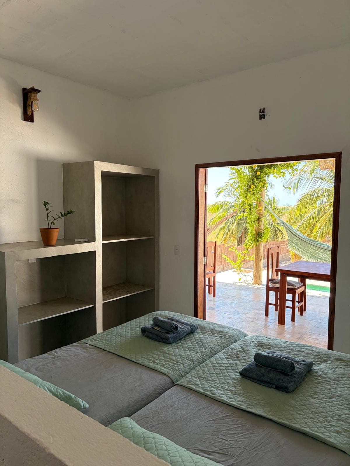 Chambre à deux lits, niches de rangement et porte ouverte sur la terrasse