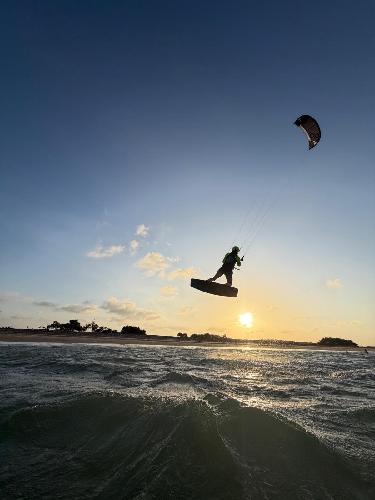 Kitesurfeur en plein saut au-dessus de l'eau, au coucher du soleil