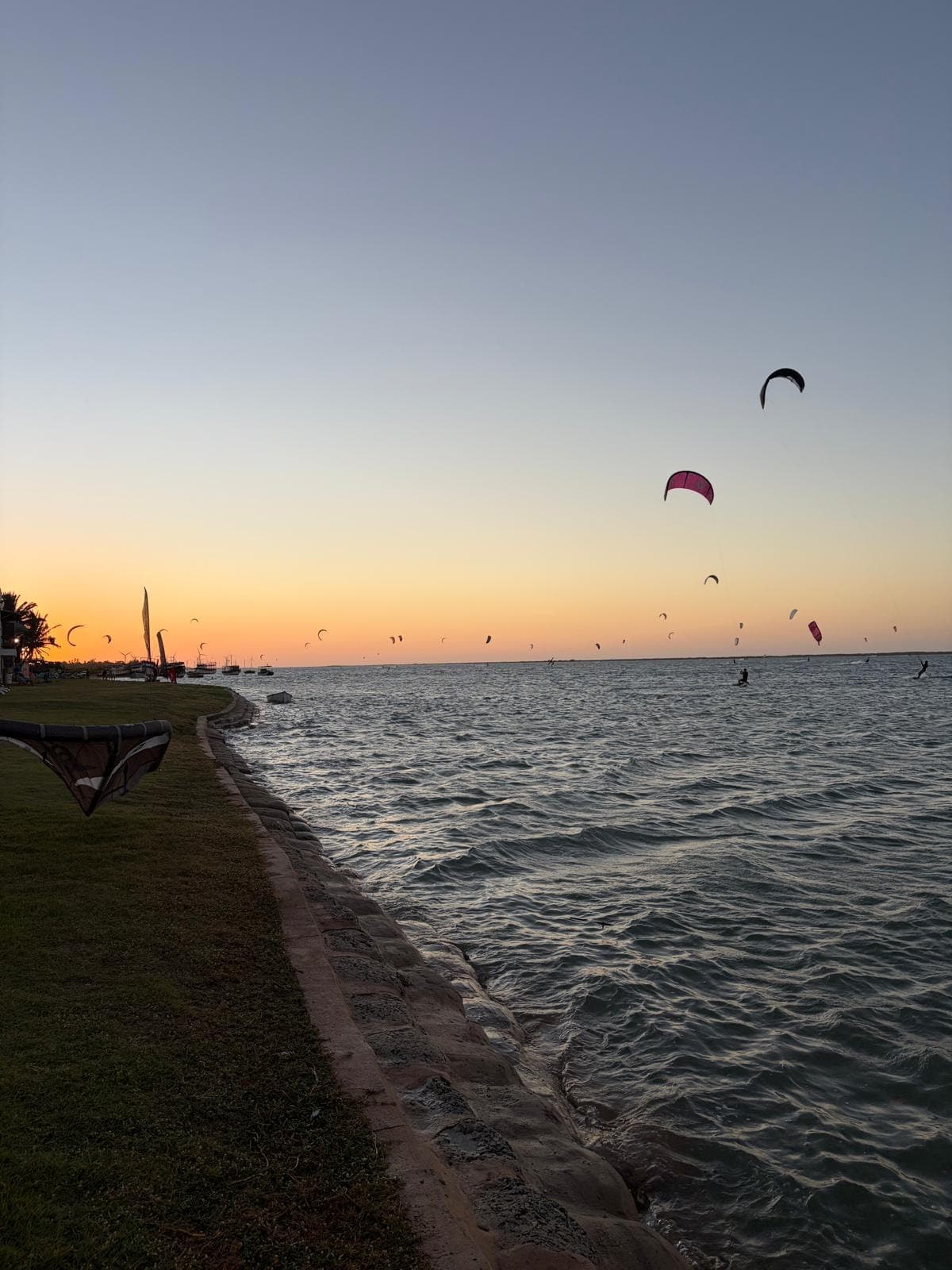 Des dizaines d'ailes de kite sur la lagune au coucher du soleil